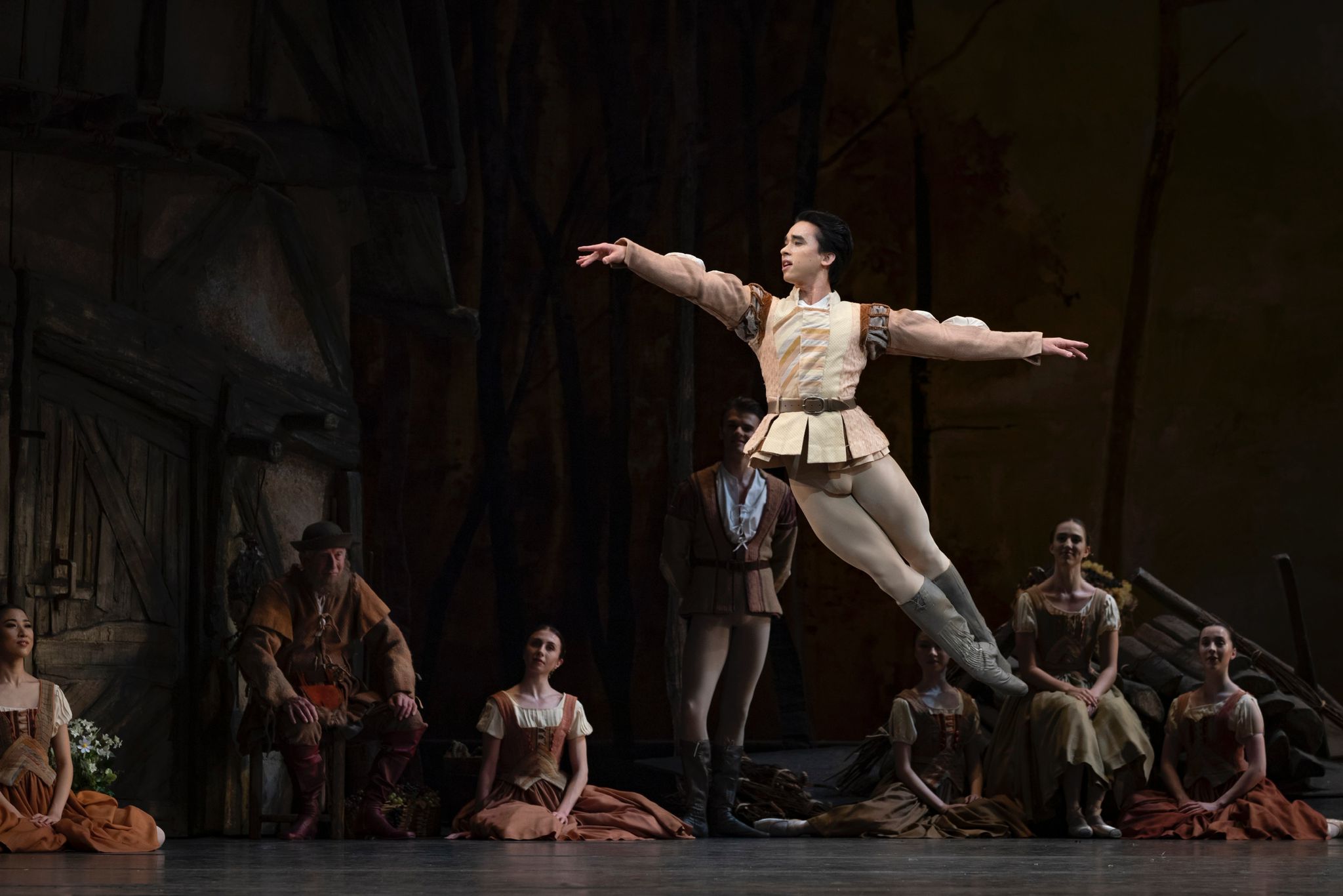 Benjamin Ella airborne on stage in a cream costume, with arms extended